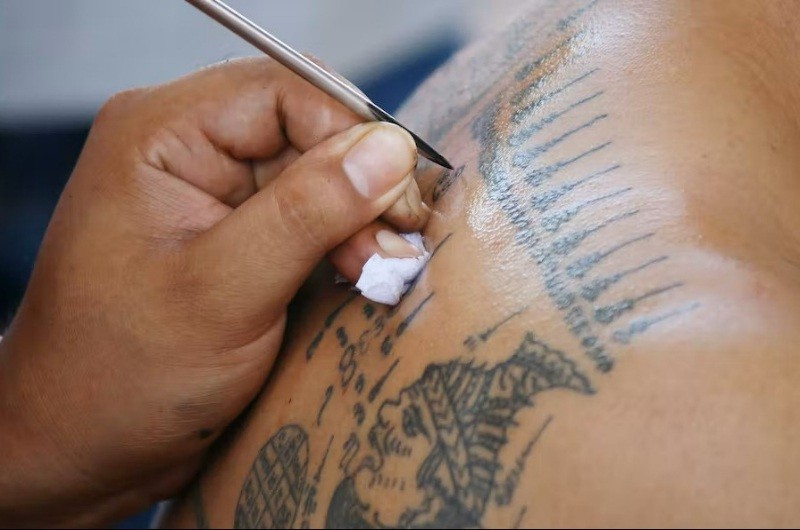 Aguja utilizada para realizar un tatuaje Sak Yant sobre la espalda