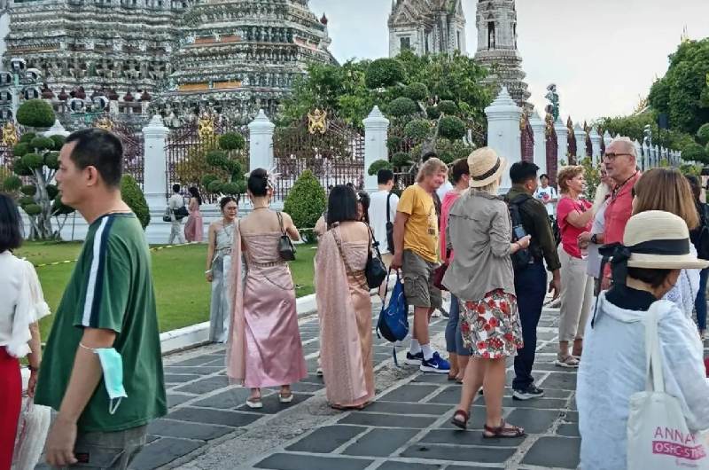 Turistas visitando Wat Arun con ropa ligera durante agosto en Bangkok