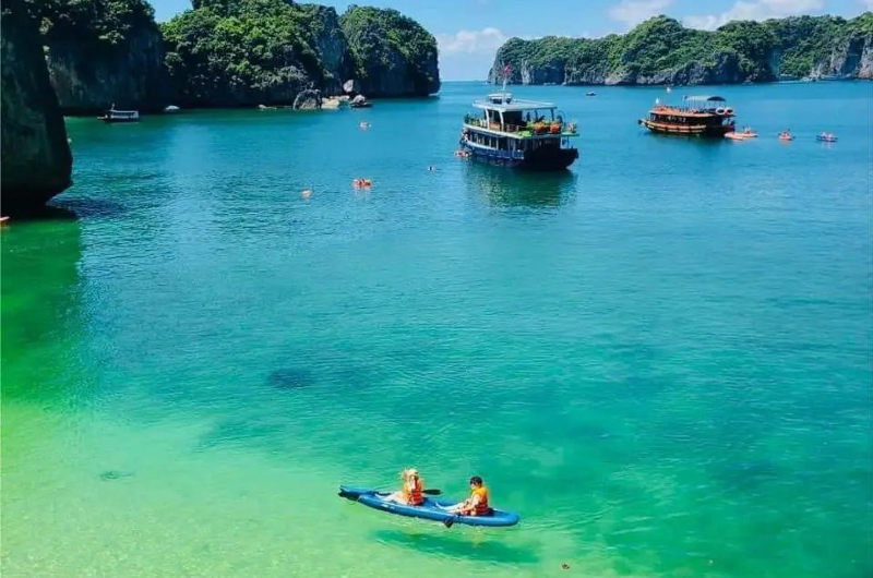 Vista de la isla de Cat Ba con aguas transparentes, barcos anclados y personas haciendo kayak en la bahía de Lan Ha en el norte de Vietnam