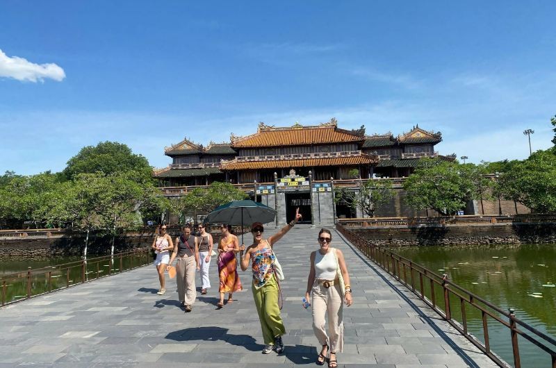 Turistas cruzando el puente hacia la Ciudadela Imperial de Hué en un día soleado