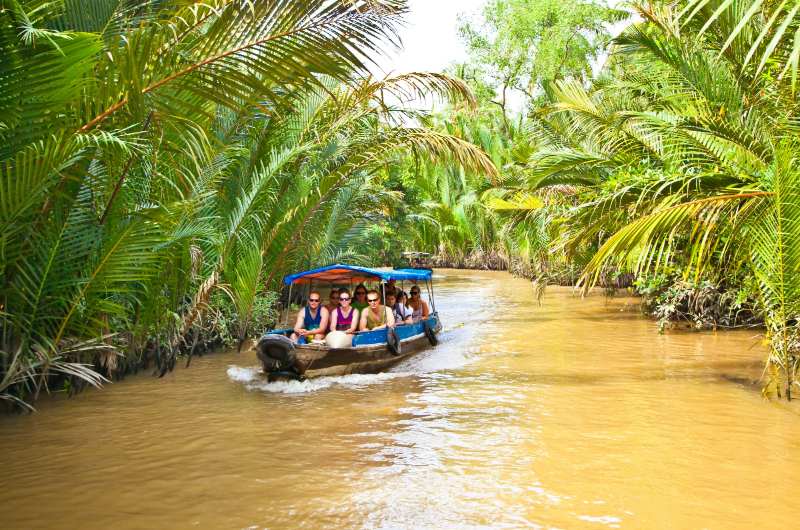 Embarcación navegando por uno de los canales del Delta del Mekong durante un día soleado