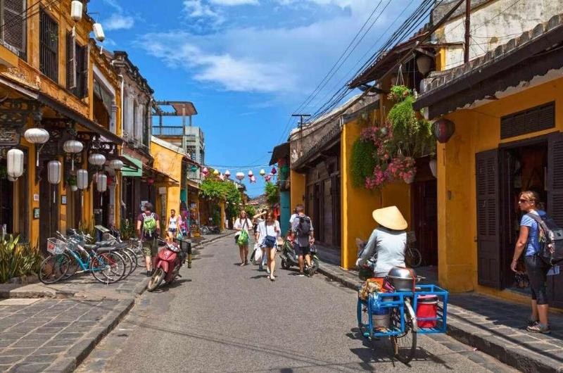 Turistas paseando por el casco histórico de Hoi An en un día soleado de mayo.