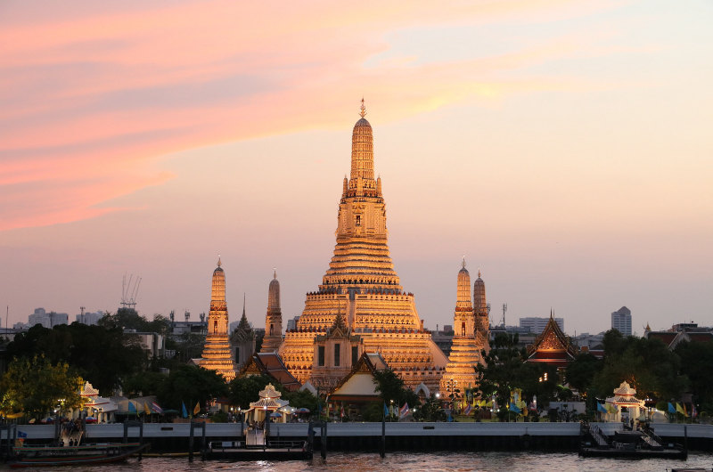 Wat Arun iluminado al atardecer a orillas del río Chao Phraya
