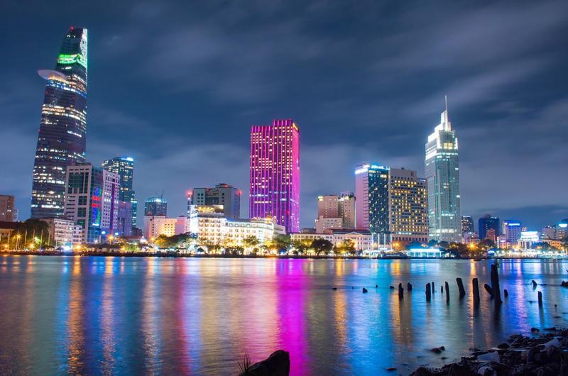 Vista nocturna de Ho Chi Minh City con rascacielos iluminados junto al río Saigón