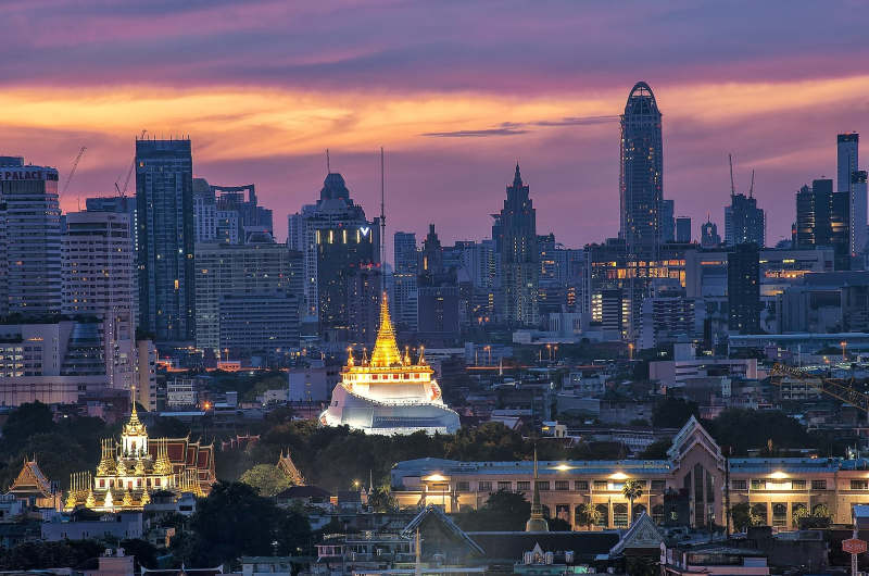 Wat Saket iluminado con los rascacielos de Bangkok al fondo