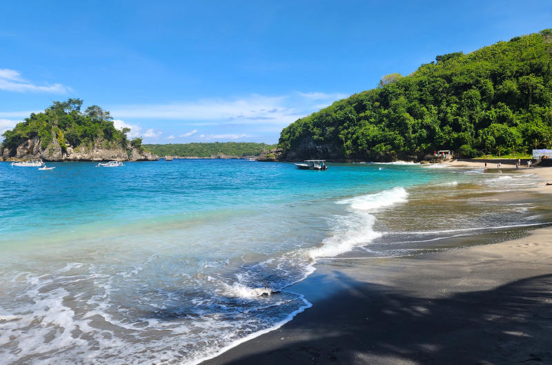 Playa de Crystal Bay en Nusa Penida con arena volcánica oscura y aguas claras