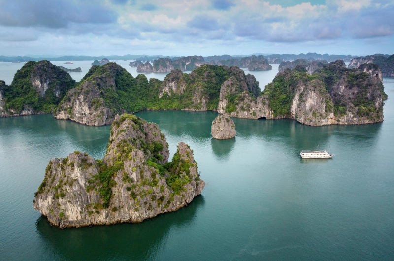 Islotes de roca caliza en la bahía de Halong con barco navegando