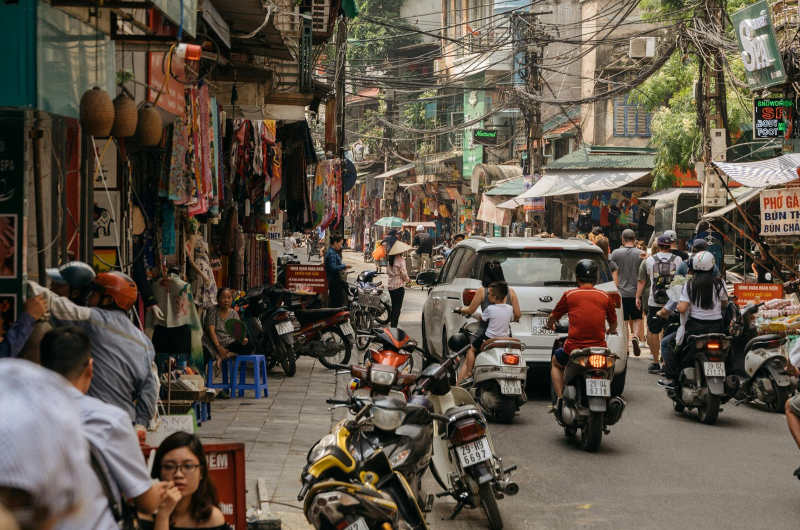 Calle del barrio antiguo de Hanoi con motos y tiendas tradicionales en Vietnam