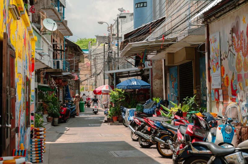 Calle con casas tradicionales y grafitis en el barrio de Talad Noi en Bangkok
