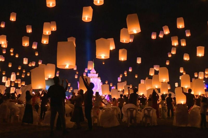 Personas lanzando linternas khom loi durante el festival Yi Peng en Chiang Mai