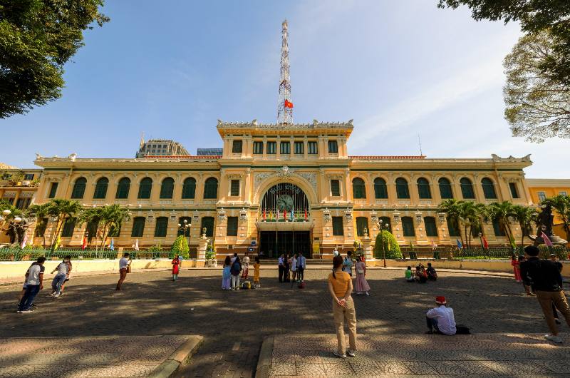 Turistas frente a la Oficina Central de Correos de Ho Chi Minh en un día soleado