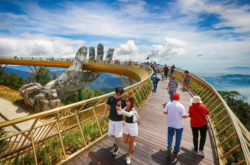 Turistas paseando por el Puente Dorado de Vietnam en un día soleado y con vistas despejadas