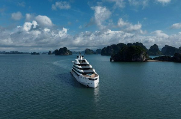 Crucero navegando por la bahía de Halong en junio con cielo azul, algunas nubes e islotes de piedra caliza.