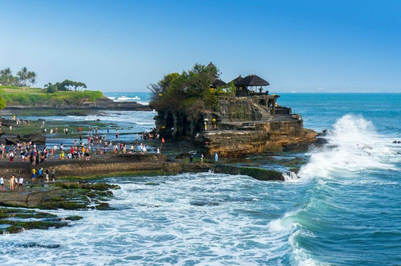 Turistas caminando hacia el templo Tanah Lot durante un viaje a Bali en julio